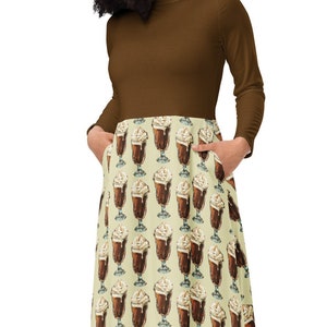 May include: A brown long-sleeved dress with a brown top and a skirt featuring a pattern of brown and white milkshakes on a light yellow background.
