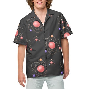 May include: A black short-sleeved button-down shirt with a pattern of pink and purple atoms. The shirt has a collar and a relaxed fit.