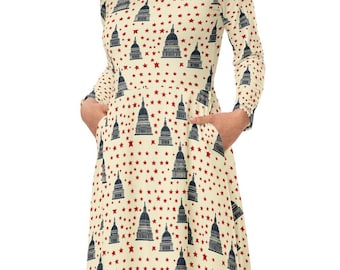 May include: A cream-colored midi dress with a pattern of red stars and blue Capitol Building silhouettes. The dress has long sleeves and pockets.
