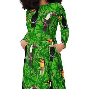 May include: A green dress with a toucan and tropical leaf print. The dress has long sleeves and pockets.