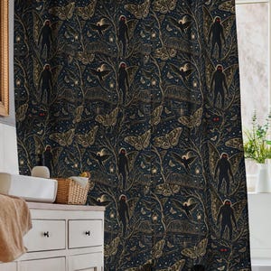 May include: A dark blue shower curtain featuring a repeating pattern of Bigfoot silhouettes, moths, and stars in gold and white. The design includes intricate line work depicting forest elements and small glowing red eyes within the dark background.