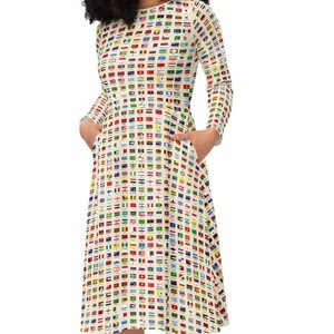 May include: A white dress with a pattern of flags from around the world. The dress has long sleeves and a flared skirt. The model is wearing white sneakers.