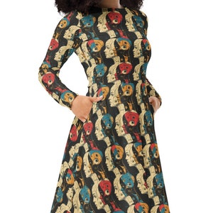 Puede incluir: Un vestido midi negro con un estampado colorido de caras. El vestido tiene mangas largas y un corpiño ajustado. La falda es acampanada y llega a la rodilla.
