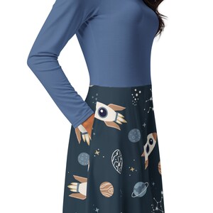 May include: A long-sleeved dress with a blue top and a navy blue skirt. The skirt has a pattern of white rockets, planets, and stars.