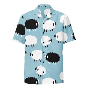 May include: A light blue short-sleeved button-up shirt with a white and black sheep pattern.