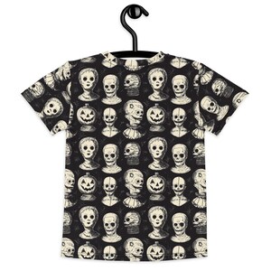 May include: Black t-shirt with a repeating pattern of white illustrations of spooky dolls and jack-o'-lanterns.