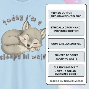 May include: Light blue t-shirt featuring a sleeping cartoon wolf with the text "today i'm a sleepy lil wolf." The shirt also includes text about the fabric and fit. The design is printed on a medium-weight fabric.