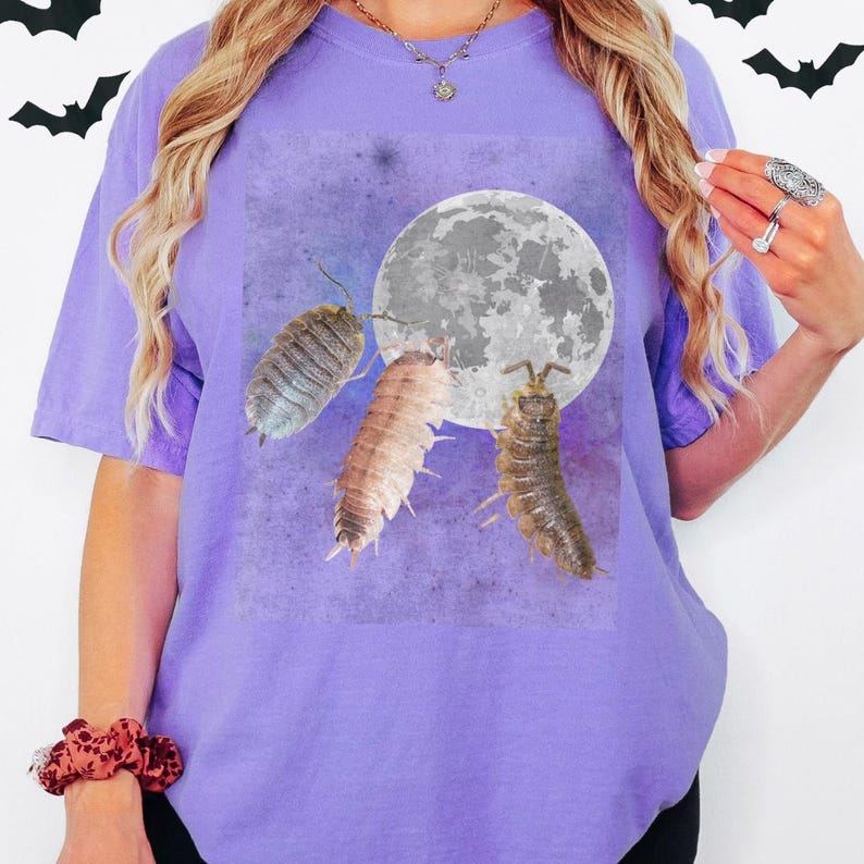 May include: A purple t-shirt with a graphic of three roly-polies crawling towards a full moon.