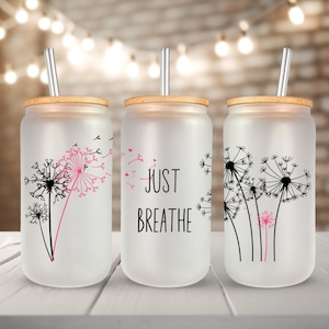 May include: Three frosted glass tumblers with bamboo lids and reusable straws. The tumblers feature a dandelion design with pink accents and the text "Just Breathe".