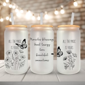 May include: Three frosted glass tumblers with bamboo lids and metal straws. Each tumbler features a different inspirational quote and a butterfly design. The quotes are "All the magic is yours", "Miracles blessings good energy love beautiful connections", and "All the magic is yours".