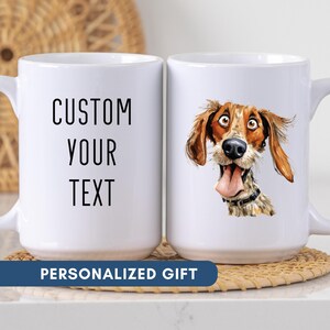 May include: Two white ceramic mugs. One mug has the text "CUSTOM YOUR TEXT" in black. The other mug features a cartoon dog with brown and tan fur, a black collar, and its tongue sticking out. The words "PERSONALIZED GIFT" are on a blue banner.