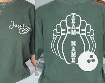 May include: Moss green t-shirt with white bowling-themed graphics. The front features the name "Jason" and a bowling ball design. The back displays a bowling pin graphic with the words "TEAM NAME" and a bowling ball.