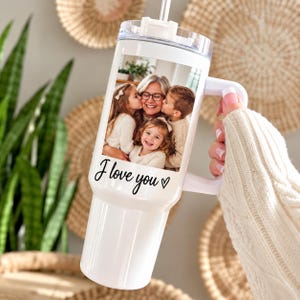May include: A white stainless steel tumbler with a handle and a clear lid featuring a straw. The front displays a color photograph of an adult and three children, with the black cursive text "I love you" and a small heart symbol printed below.