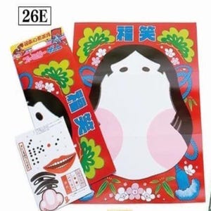 May include: A red and green game board with a white face on it. The face has pink cheeks and black hair. The game board has the Japanese characters for "Happy" and "Smile" on it. The game board is labeled with the number "26E".