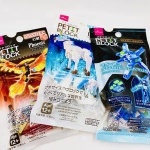 May include: Three packages of Petit Block building sets. One features a phoenix, another a unicorn, and the third a robot. Each package has a different color scheme and includes the age range of 12+.