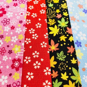 May include: Close-up of four patterned ribbons. The ribbons feature floral and leaf designs in pink, red, black, and blue. The floral patterns include white and yellow flowers. The leaf pattern is in yellow, green, and orange.