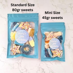 May include: Two clear plastic bags filled with colorful sweets. The larger bag, labeled "Standard Size 80g sweets," contains a variety of candies, including star-shaped and ring-shaped treats. The smaller bag, labeled "Mini Size 45g sweets," has a similar assortment. Both bags have a sticker that reads "Harry's 8th Birthday."