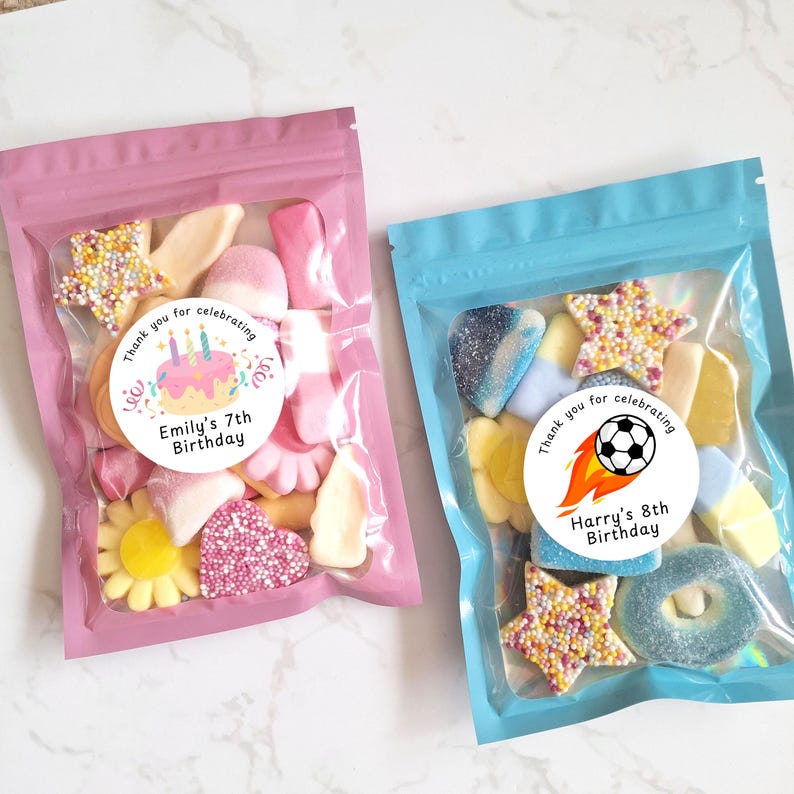 May include: Two clear plastic bags filled with colorful candies. One bag is pink and features a sticker that reads "Emily's 7th Birthday." The other bag is blue and has a sticker that says "Harry's 8th Birthday."