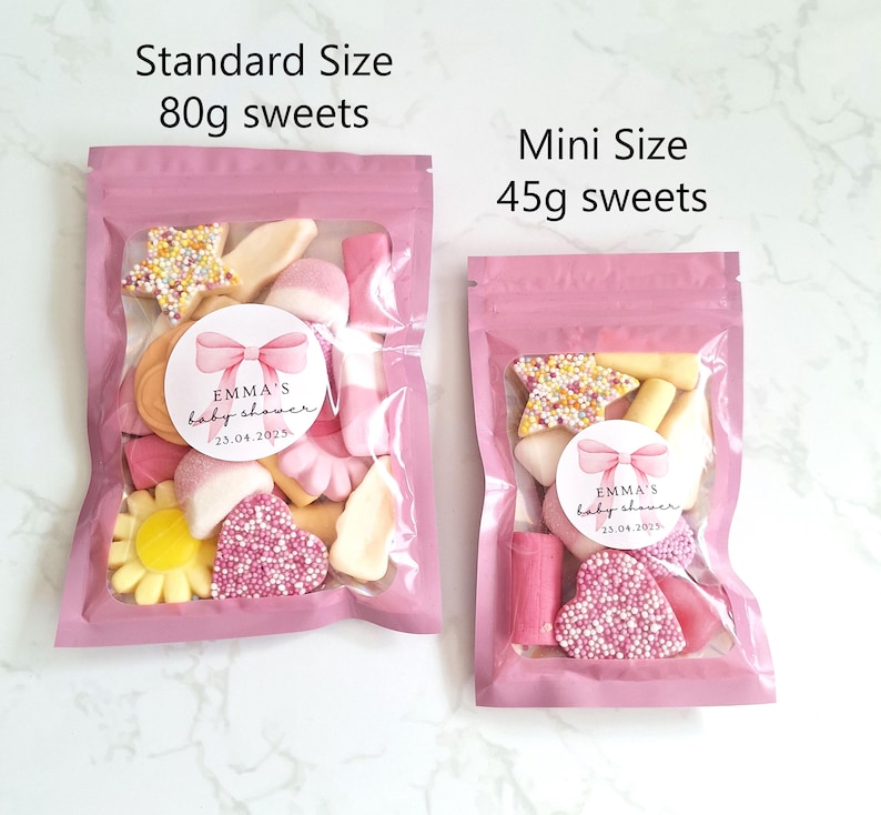 May include: Two pink cellophane bags filled with sweets. The larger bag, labeled "Standard Size," contains 80g of sweets, while the smaller bag, labeled "Mini Size," contains 45g. Each bag has a sticker that reads "EMMA'S baby shower 23.04.2025."