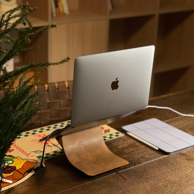 LOOMMA brand cherry wood laptop stand on a desk holding an Apple MacBook, featuring elegant craftsmanship and a sturdy build for a stylish and functional workspace