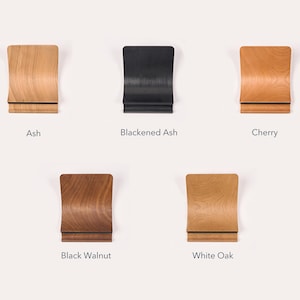 Collection of five LOOMMA laptop stands crafted from distinct woods: light ash, dark stained ash, reddish cherry, deep brown walnut, and pale robust white oak, each showcasing unique grain and color