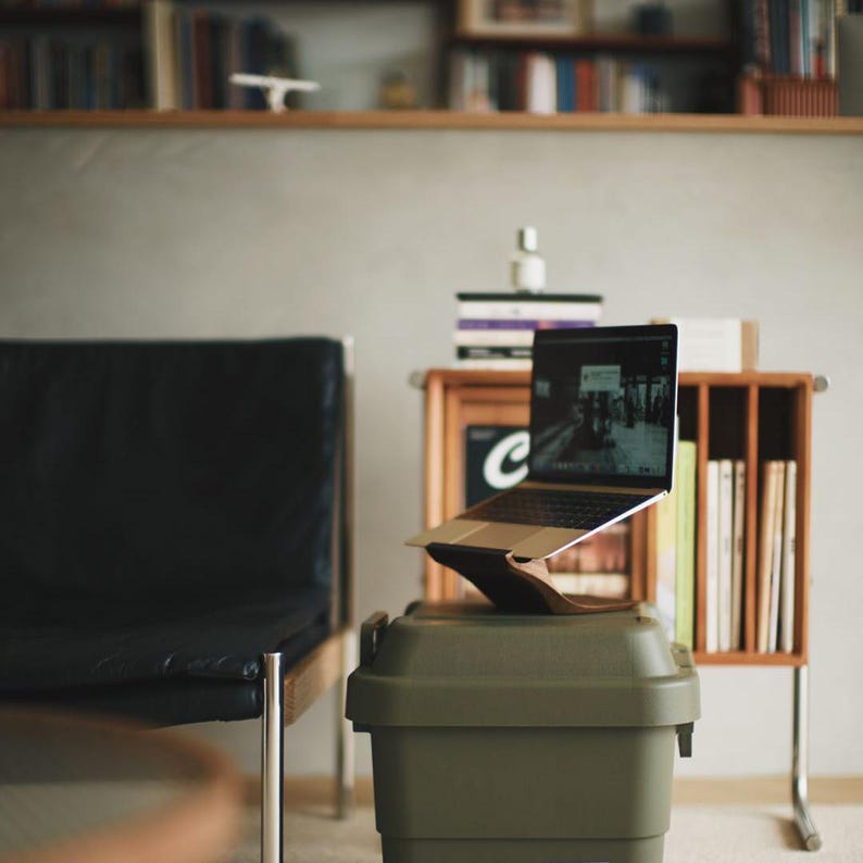 LOOMMA brand walnut wood laptop stand on a storage box supporting a laptop in a living room, creating a comfortable and harmonious environment