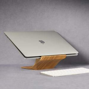 LOOMMA brand walnut wood laptop stand on a desk, supporting an Apple computer with a sleek gray background, showcasing the natural elegance and sturdy design of the stand(1)