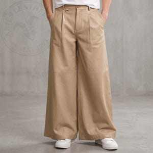 May include: Beige wide-leg leather trousers featuring a high-waisted design with front pleats, a button closure, a small metal D-ring detail at the waistband, and a horizontal seam across the mid-thigh. The Aries Leathers logo is visible.