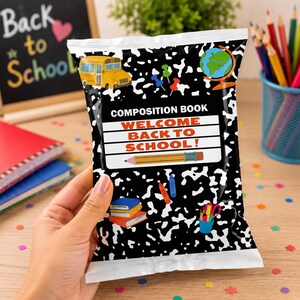 May include: A rectangular snack bag with a black and white composition notebook pattern. The center features a white label with the text COMPOSITION BOOK and WELCOME BACK TO SCHOOL! along with a yellow school bus, globe, and pencil graphics.