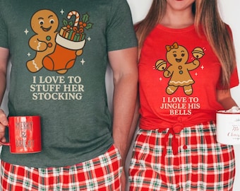 May include: Matching Christmas pajamas set. A person wears a green t-shirt with a gingerbread man graphic and the text "I LOVE TO STUFF HER STOCKING". Another person wears a red t-shirt with a gingerbread woman graphic and the text "I LOVE TO JINGLE HIS BELLS". Both wear red plaid pants.