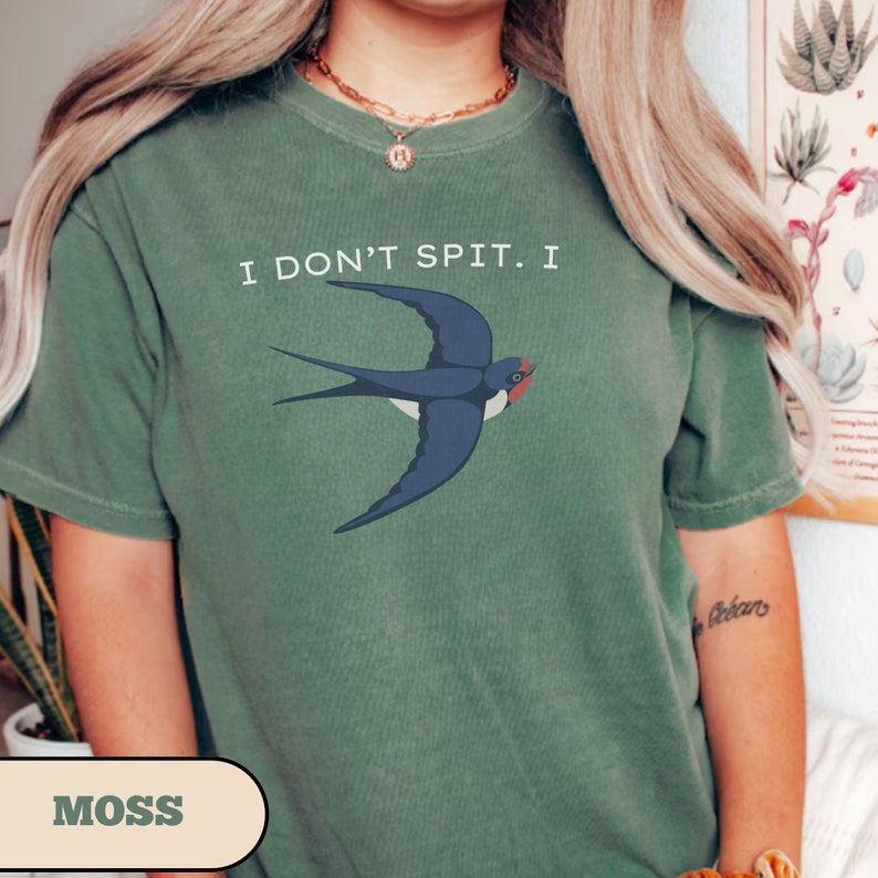 May include: A moss green t-shirt with the text "I don't spit. I" and a blue swallow illustration.