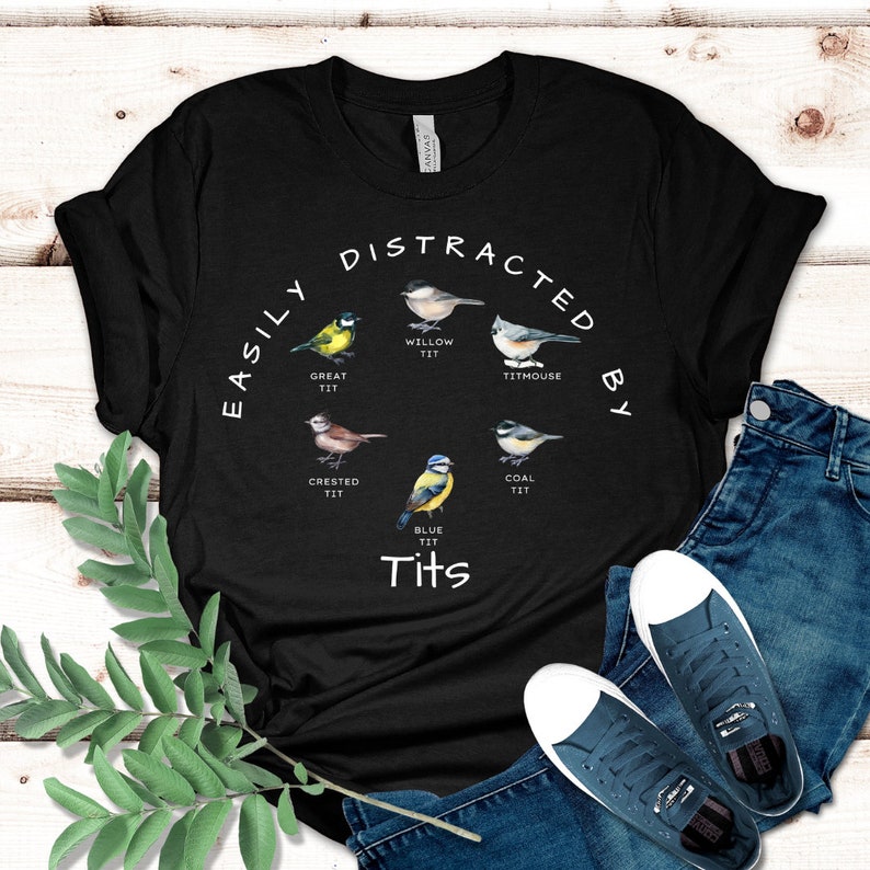 May include: Black t-shirt with the text "Easily Distracted By Tits" and illustrations of different types of birds, including a blue tit, a great tit, a willow tit, a coal tit, a crested tit, and a titmouse.
