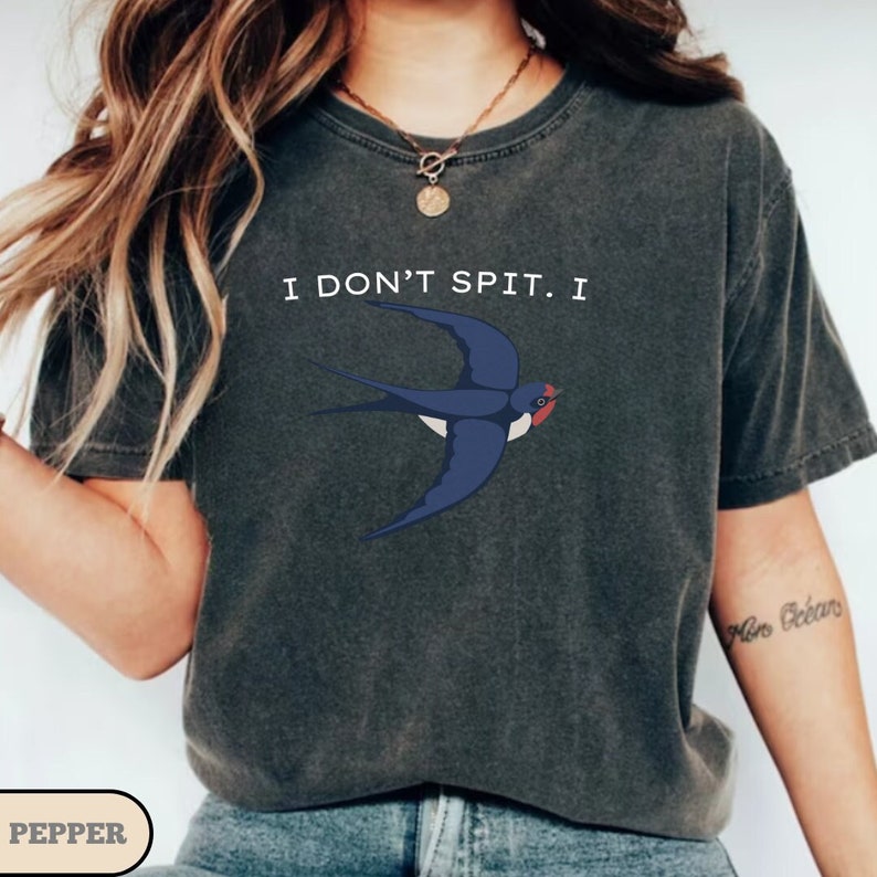 May include: A dark gray t-shirt with a white swallow graphic and the text "I don't spit I".