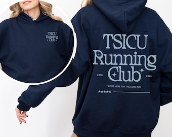May include: Navy blue hooded sweatshirt with the text "TSICU Running Club" in white with a star design. The text "ESTD" and "2025" are also included on the sweatshirt. The text "WE'RE HERE FOR THE LONG RUN" is printed below the main text.