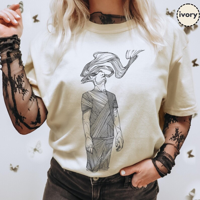 Comfort Colors® ivory T-shirt featuring Prakash’s hand-drawn line-art figure; styled with mesh sleeves and butterflies backdrop to show print scale and everyday wear.