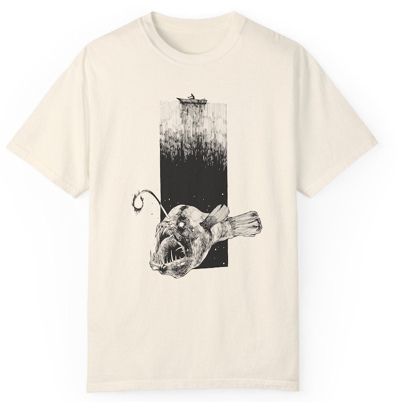 product view of comfort colors 1717, color ivory 
Hand-drawn anglerfish tee featuring a deep ocean scene with a boat and fisherman on the surface. Perfect for nature lovers, fans of retro 90s and 2000s style, and grunge fashion enthusiasts.