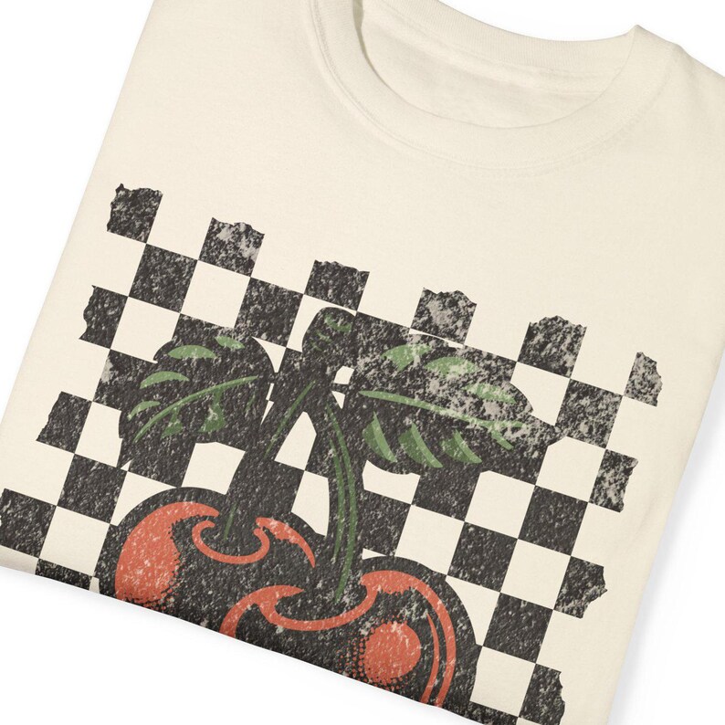 Close-up of folded checkered cherry shirt – Comfort Colors fabric, distressed streetwear vibes, and bold retro cherries print.