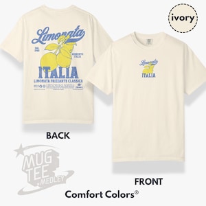 May include: Ivory-colored t-shirt featuring a front and back view. The back displays a large graphic with the word "Limonata" in blue, lemons, and the word "Italia." The front has a smaller version of the same design. The shirt is from Comfort Colors.