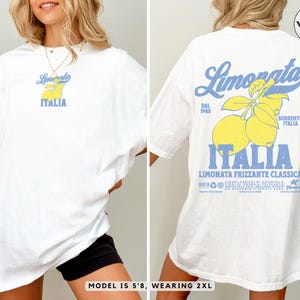 White Comfort Colors® t-shirt with vintage Italian lemonade back print and small citrus chest logo. Oversized fit styled by a 5’8” model wearing size 2XL. Retro foodie shirt for travel and summer looks.