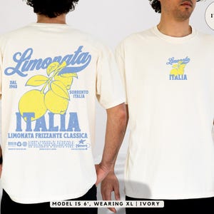 Model wearing ivory Comfort Colors® t-shirt with small front chest print and bold lemon-themed Italian back print. Retro graphic tee inspired by Sorrento and Amalfi Coast. Model is 6’, wearing size XL.