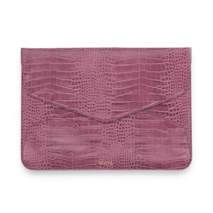May include: A pink crocodile embossed leather envelope clutch with the word "NOTIQ" embossed in gold on the bottom.