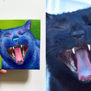 May include: A vibrant painting of a blue cat yawning, set against a green background. The cat's mouth is wide open, revealing its pink tongue and sharp teeth. The artwork is held by a person's hand, showcasing the canvas's square shape.