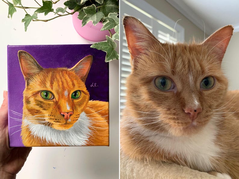 May include: A square canvas painting of an orange tabby cat with green eyes and a white chest, set against a purple background. The painting is held up next to a real orange tabby cat with green eyes.