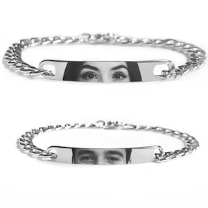 Könnte beinhalten: Zwei silberfarbene Metallkettenarmbänder mit einer flachen, rechteckigen Mittelplatte. Jede Platte zeigt eine schwarz-weiße Fotogravur eines menschlichen Augenpaares, wobei ein Armband einen weiblichen und das andere einen männlichen Blick zeigt.
