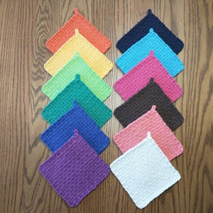 May include: A set of 12 colorful crocheted pot holders in a rainbow pattern. The pot holders are square shaped and have a loop on the top for hanging.
