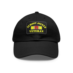 May include: Black baseball cap with a curved brim. The cap features a rectangular patch with the words "ALMOST JOINED VETERAN" in yellow lettering. The patch also includes a red, white, and yellow flag design.