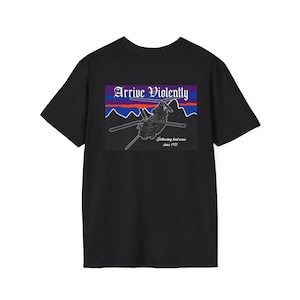 Pode incluir: Camiseta preta com um gráfico de um helicóptero voando sobre uma cordilheira. O gráfico inclui o texto "Arrive Violently" e "Delivering bad news since 1977".
