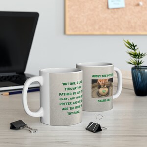 Puede incluir: Taza de cerámica blanca con un diseño verde y blanco. La taza presenta una cita de la Biblia, Isaías 64:8, "Pero ahora, oh Señor, tú eres nuestro Padre; nosotros somos el barro, y tú eres el alfarero; y todos nosotros somos la obra de tus manos." La taza también presenta una imagen de un torno de alfarero con una mano dando forma a la arcilla.