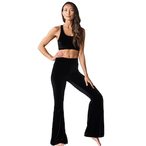 May include: Black velvet bell bottom pants with a high waist. The pants are made of a soft, stretchy fabric and have a wide leg.