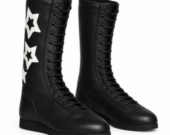 Könnte beinhalten: Ein Paar schwarze wadenhohe Stiefel mit Schnürung vorne, schwarzen Ösen und schwarzen Schnürsenkeln. Die Außenseite der Stiefel ist mit drei vertikal angeordneten weißen Sternen verziert. Die Stiefel haben eine flache schwarze Sohle und eine runde Zehenpartie.